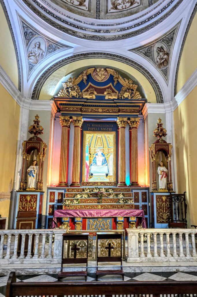 Elaborate Catholic church altar with gold detailing, statues, and Latin inscription inside a historic chapel