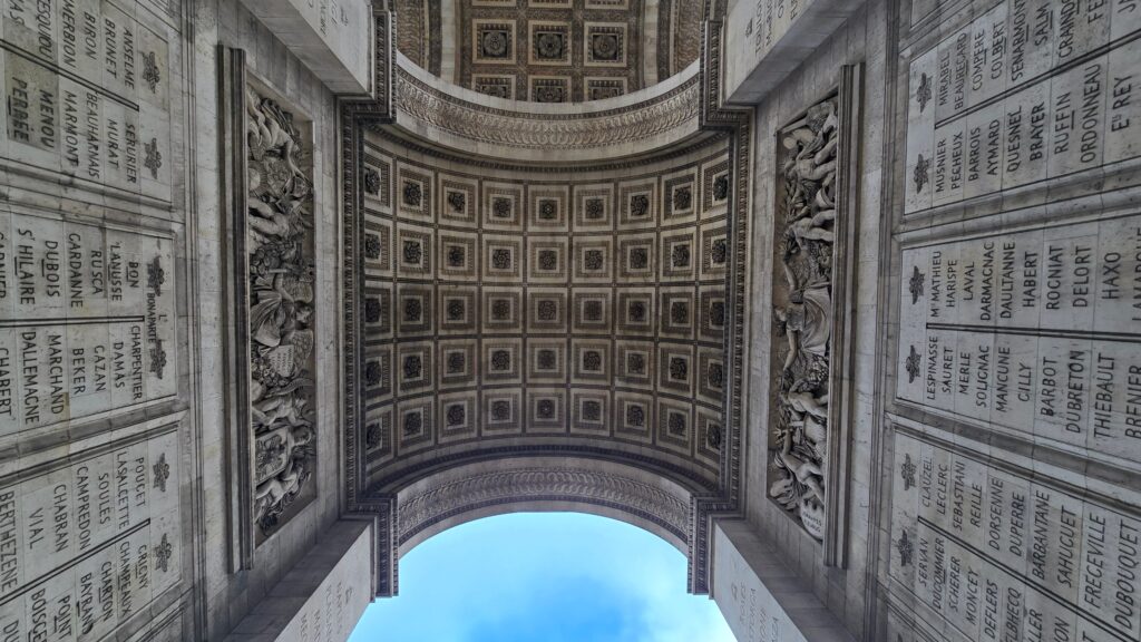 A view from below an intricately designed archway featuring ornate ceilings and engraved memorial plaques.