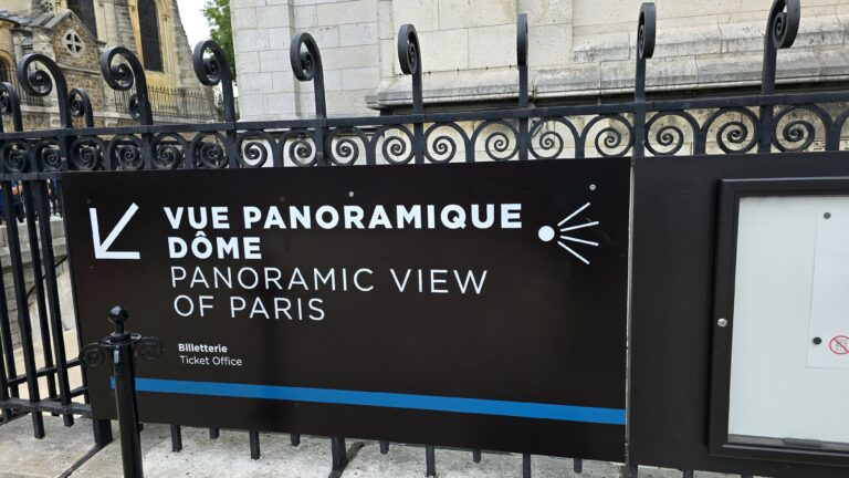 A sign indicating the "Panoramic View" attraction in Paris, featuring both French and English text, along with a ticket office reference.