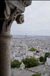 A scenic view of Paris showcasing the Eiffel Tower in the distance, framed by an ornate stone structure in the foreground.