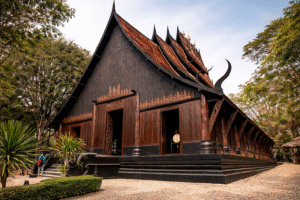 The White Temple, Chiang Rai A majestic wooden temple with ornate carvings and a distinctive roof, surrounded by greenery.