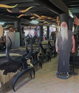Baan Dam: The Black House Museum Interior view of a workshop filled with horned furniture and a life-sized cutout of a bearded man.