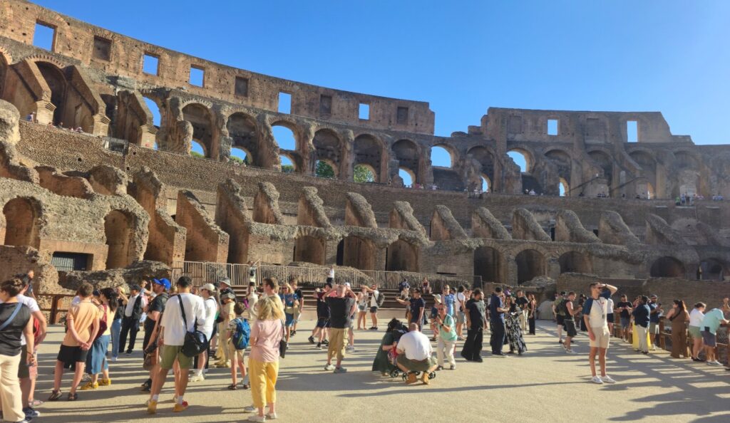 Visitors marvel at the ancient architecture of the Colosseum under a clear blue sky.