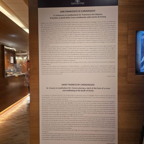 Informative display about Caravaggio's painting "Saint Francis in meditation," detailing its significance and historical context in both Italian and English.