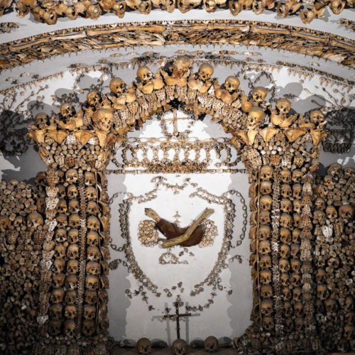 A detailed view of an ornate chapel interior decorated with human bones, showcasing intricate patterns and designs created from skulls and skeletons.