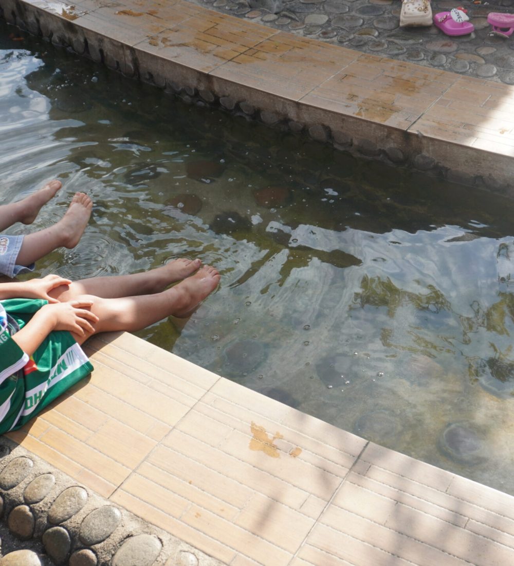 The White Temple, Chiang Rai Two children sitting by a shallow water pool, dipping their feet while enjoying a sunny day.