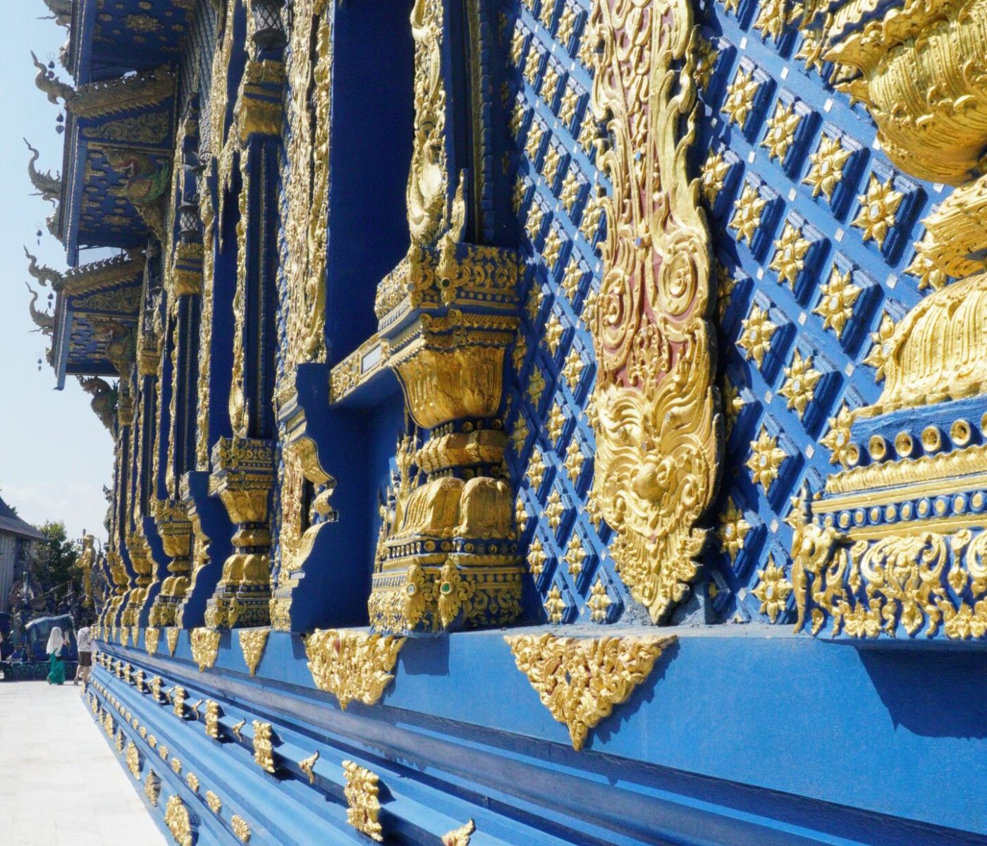Close-up view of an ornate blue wall adorned with intricate gold details and patterns, showcasing traditional architectural design.