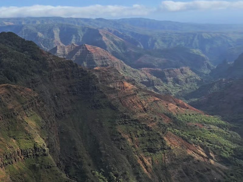 A breathtaking view of layered mountains and lush valleys under a partly cloudy sky.