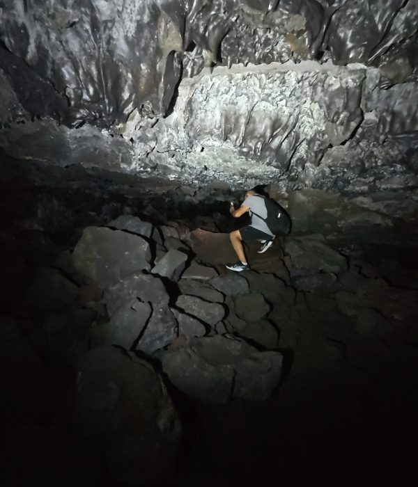 A person navigating through rocky terrain in a dimly lit cave.