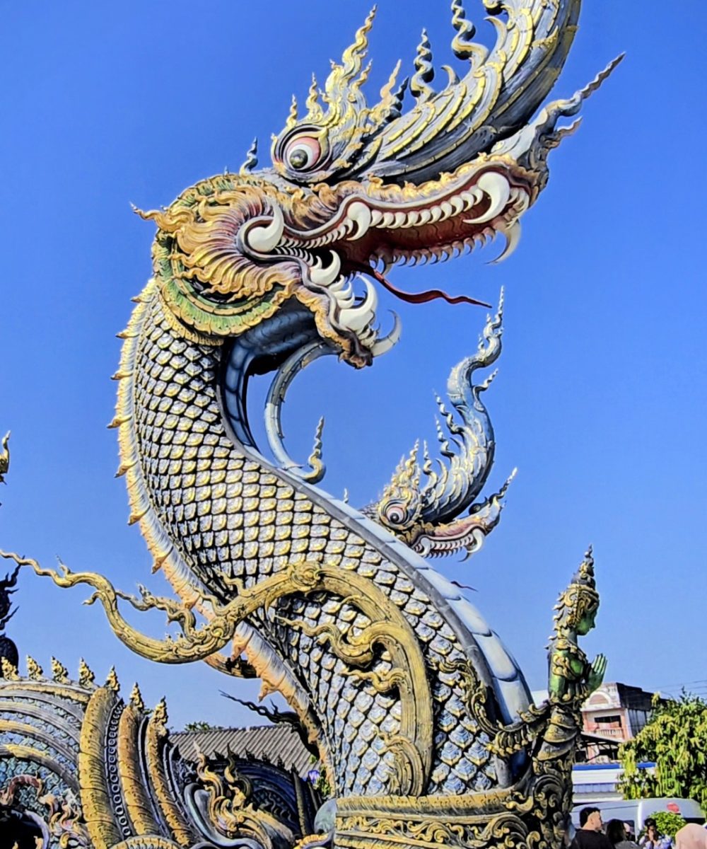 Intricate dragon sculpture adorned with vibrant colors and ornate detailing, set against a clear blue sky.