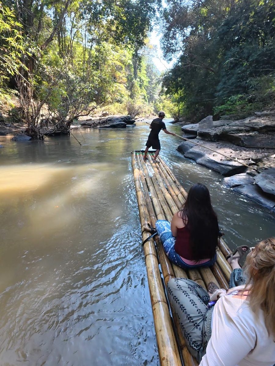 Overnight Stay At Chai Lai Orchid Elephant Sanctuary in Thailand A group enjoying bamboo rafting on a serene river surrounded by lush greenery.