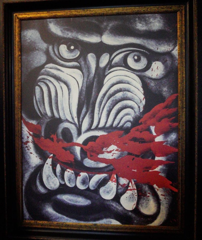 Baan Dam: The Black House Museum A striking artwork featuring a distorted face with bold contrasts in black and white, accented by splashes of red, evoking strong emotions and a primal aesthetic.