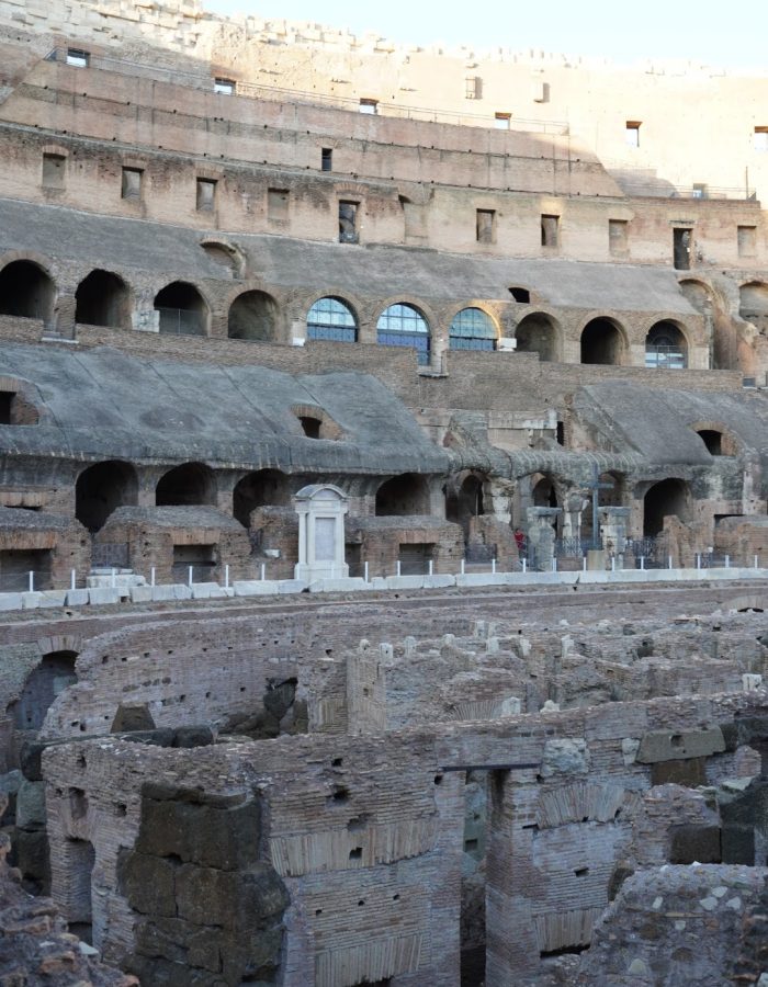 A view of the interior of the Colosseum showcasing ancient stone structures, archways, and the remnants of historical architecture.
