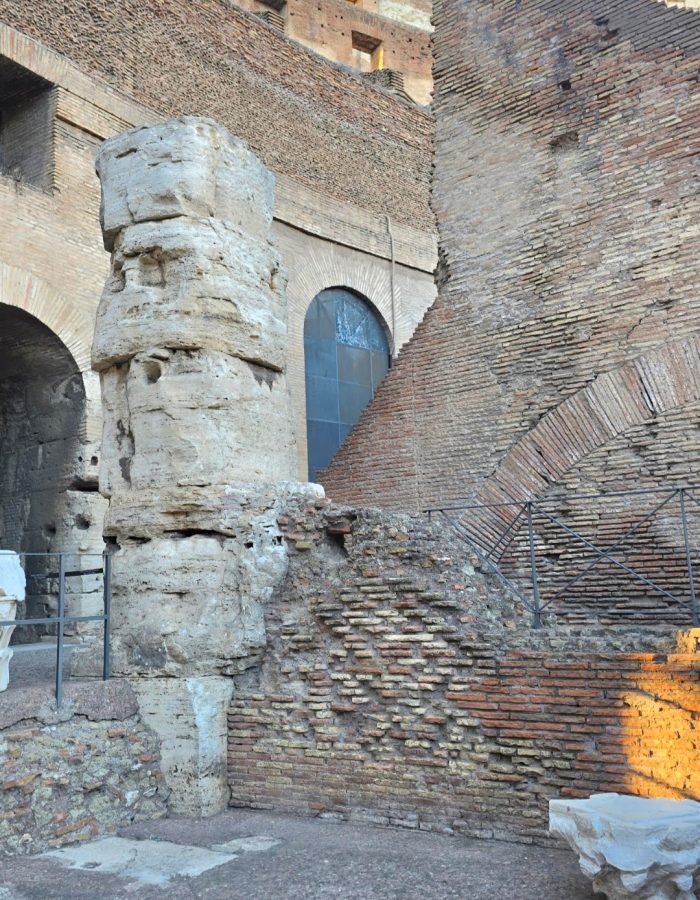 A close-up view of eroded stone walls and columns inside the ruins of a historical structure, showcasing intricate brickwork and the interplay of light and shadows.
