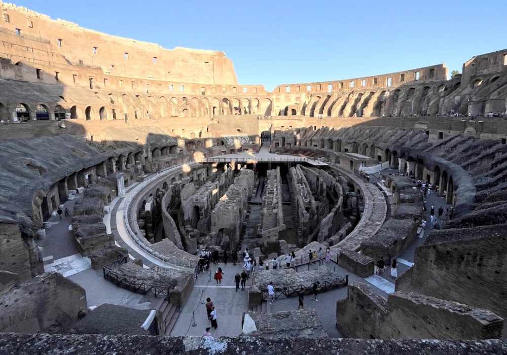 Aerial view of the Colosseum's interior showcasing ancient stone structures and visitors exploring the site.