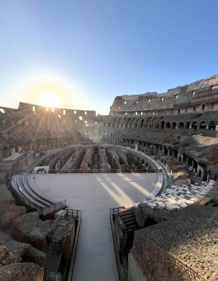 A stunning view of the interior of the Colosseum, illuminated by the setting sun, highlighting its architectural grandeur and historic ruins.