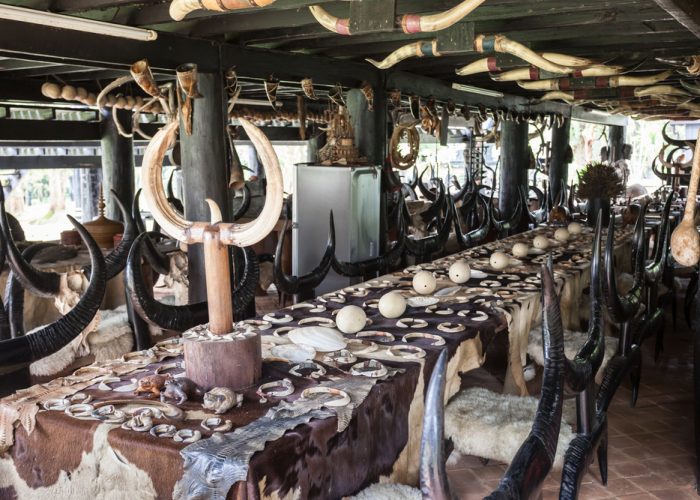 Baan Dam: The Black House Museum An elaborately decorated dining space featuring a long table adorned with decorative objects, animal hides, and intricately designed chairs with horns.